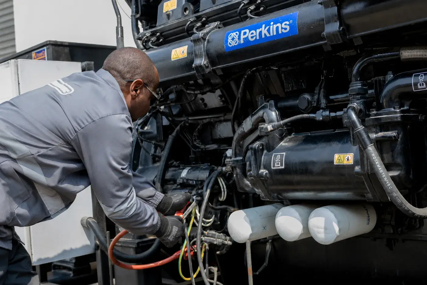 Powermec technician servicing a Perkins diesel generator on site